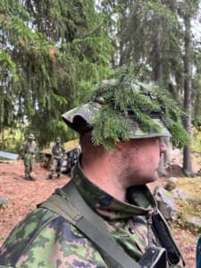 Naamioitunut mies sivuprofiilissa metsässä