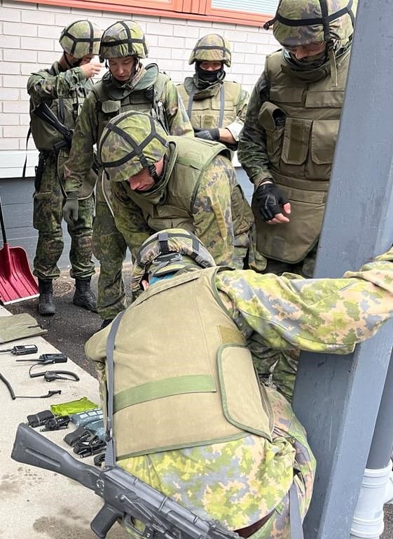 Ryhmä sotilasasuisia henkilöitä tutkii jotain maassa olevaa asiaa