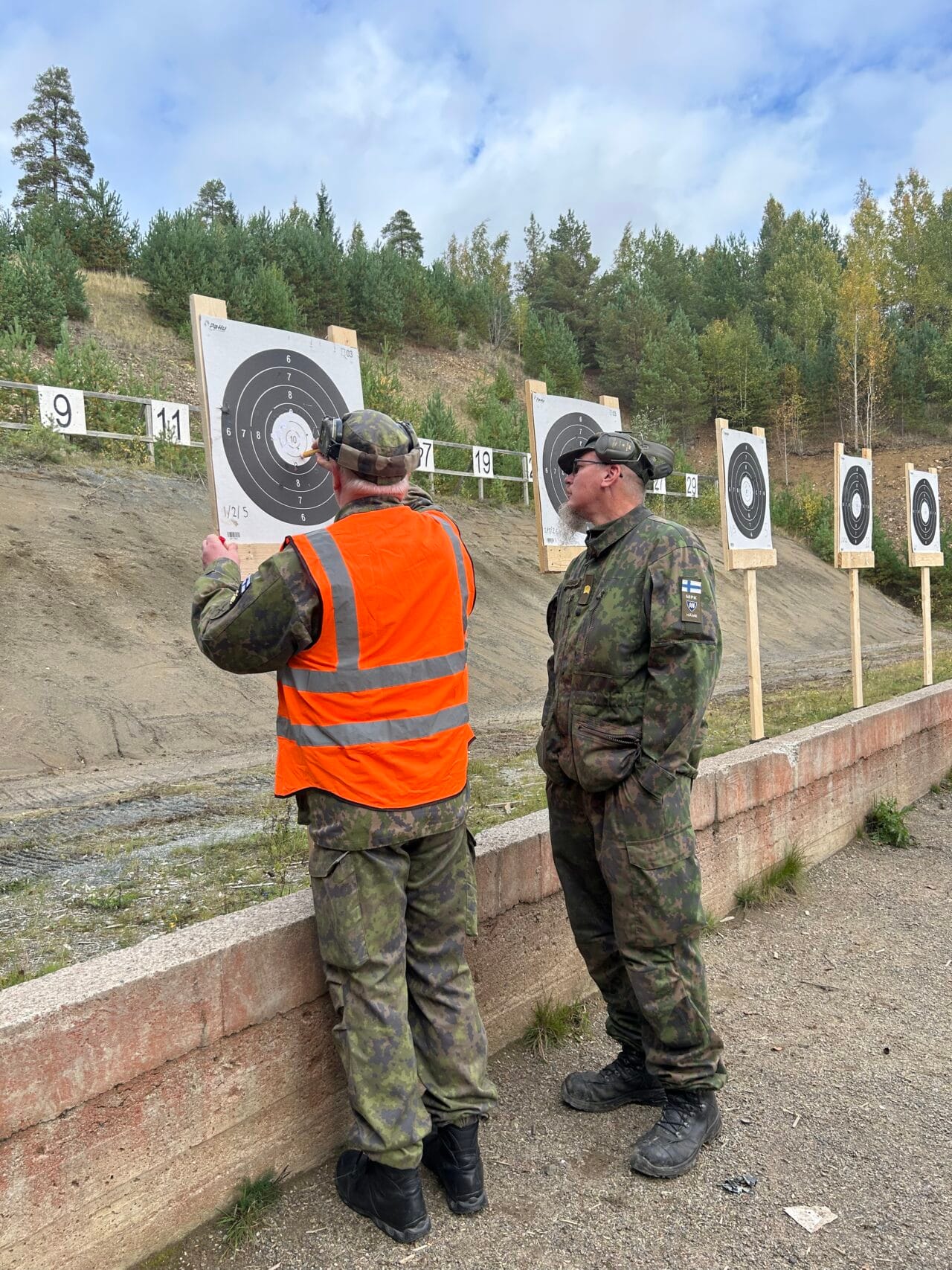 Miehet katsomassa ampumataulusta ammunnan tuloksia