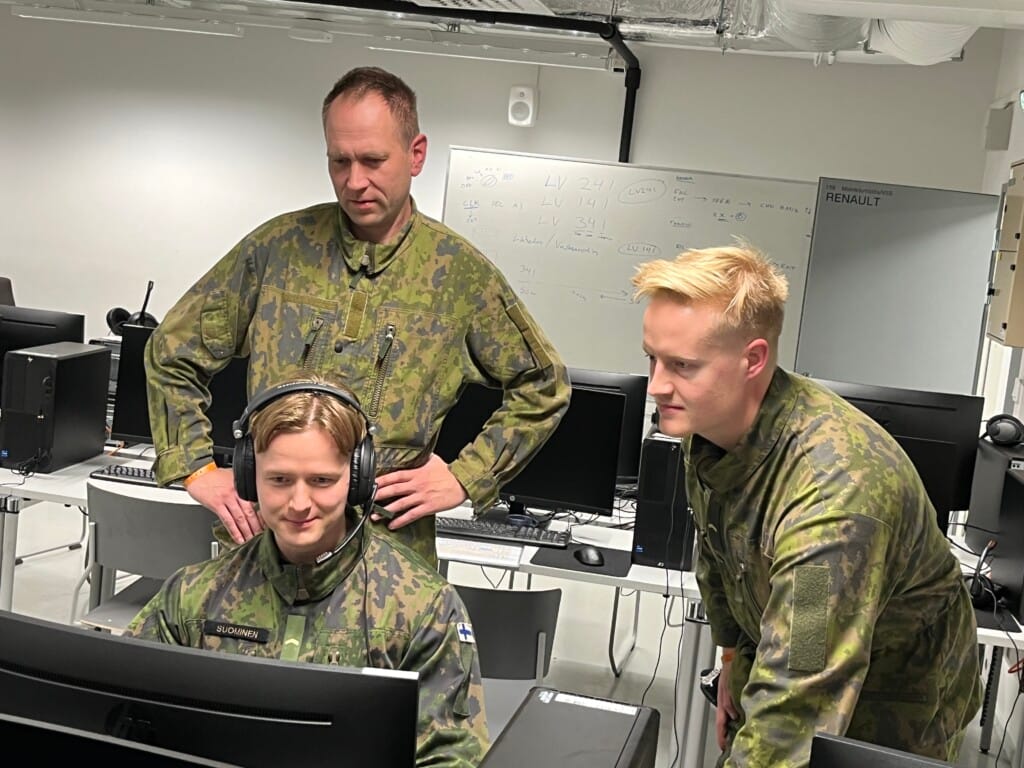 Ryhmä maastoasuisia miehinä tietokoneen äärellä