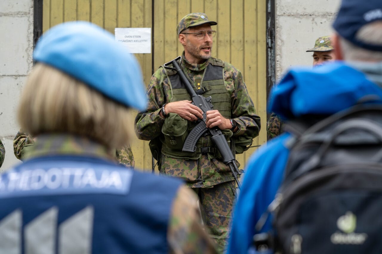 Mies maastopuvussa ulkona puhuu ihmisille