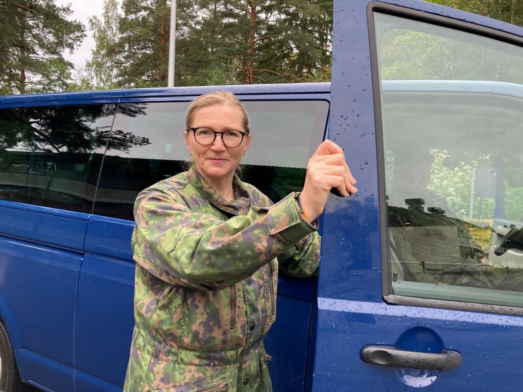 Maastopukuinen nainen pakettiauton etuovelle