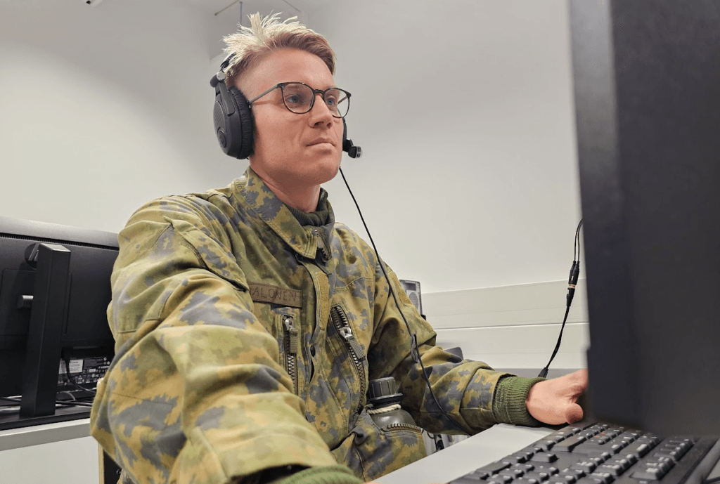 Mies kuulokkeet päässä tietokoneen näytön edessä