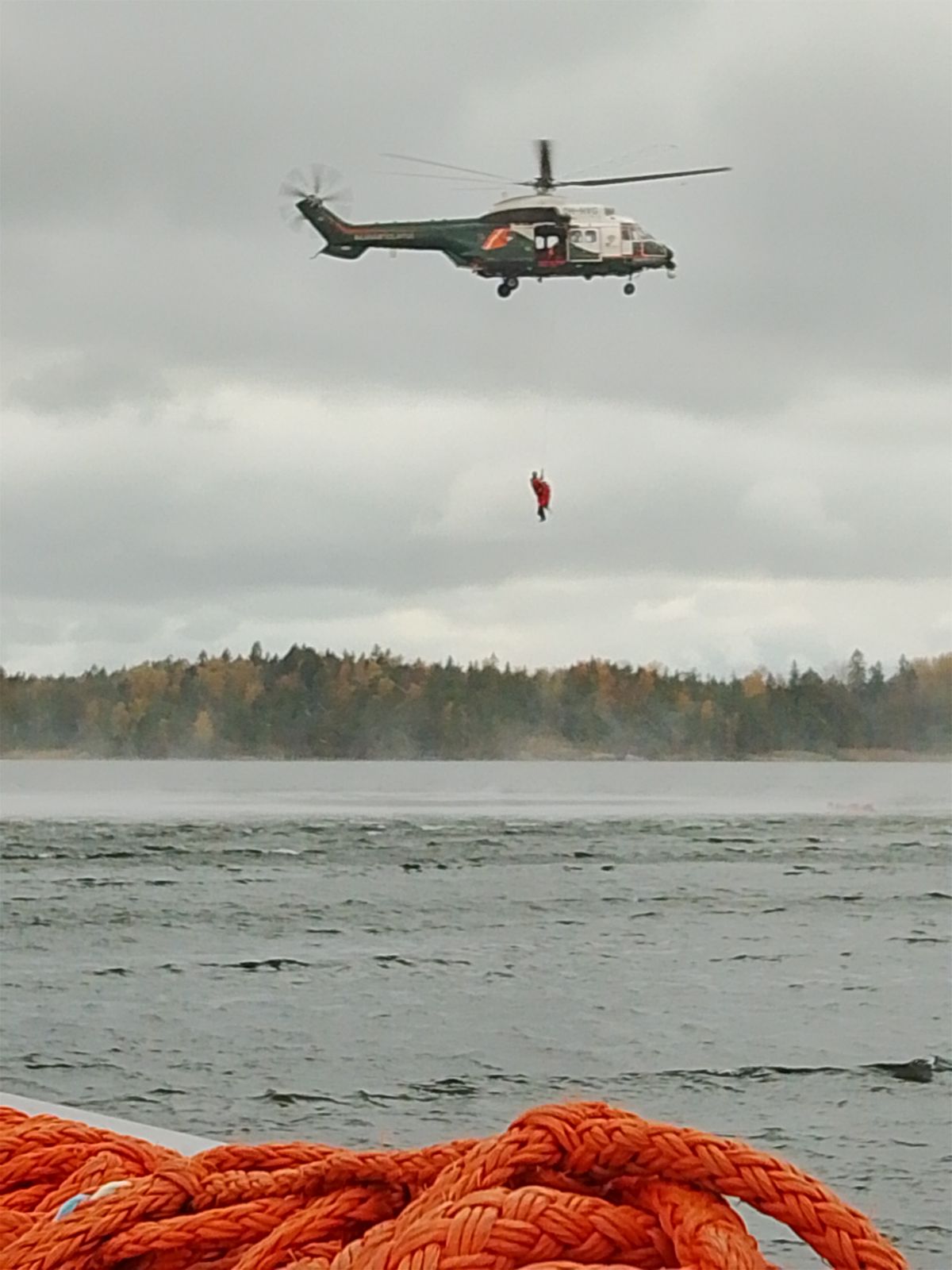Rajavartiolaitoksen helikopteri nostaa kurssilaista merestä yläilmoihin